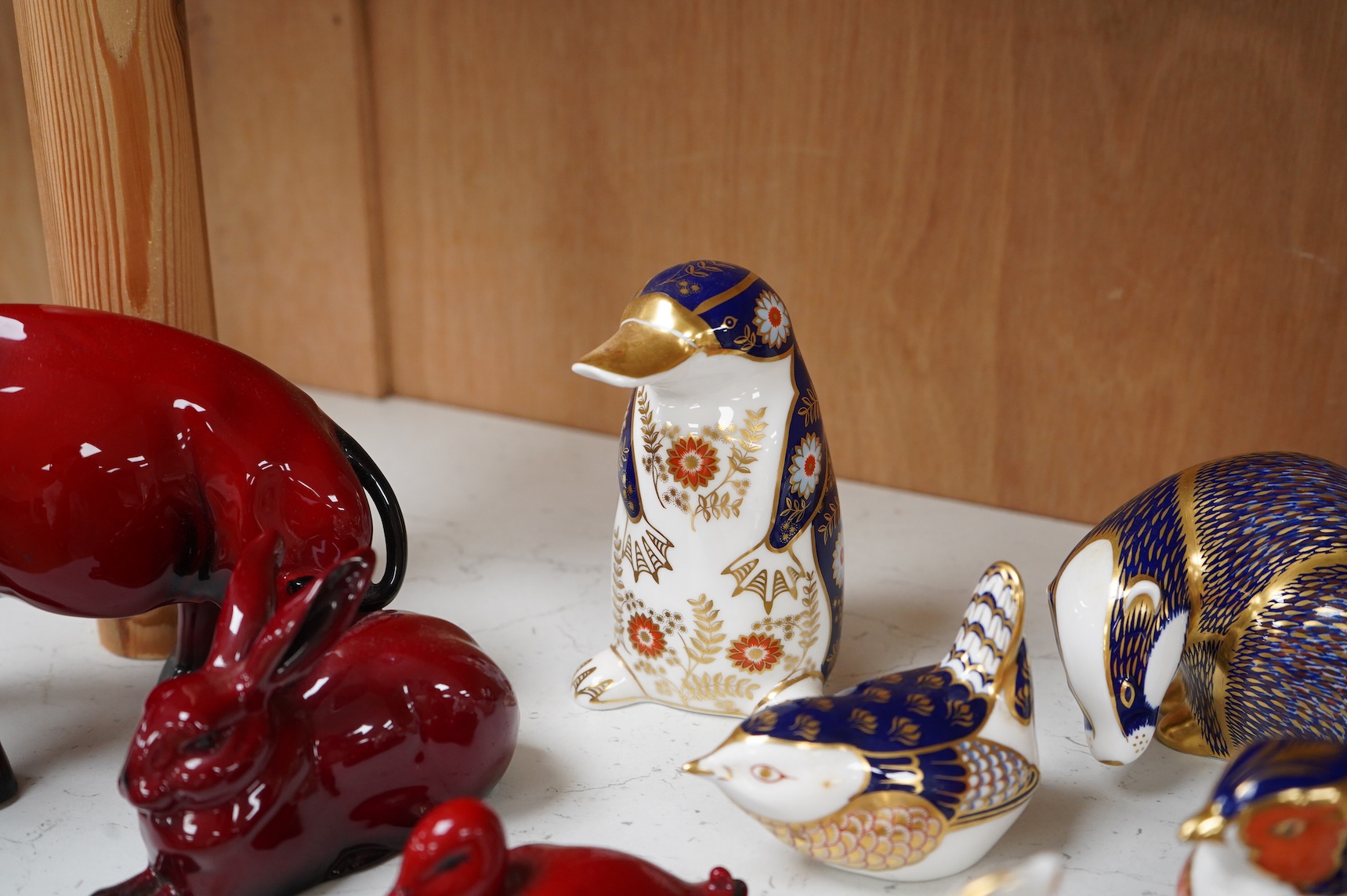 A collection of Royal Crown Derby Imari pattern paperweights, to include penguin and badger, together with three Doulton flambé animals, largest 19cm wide